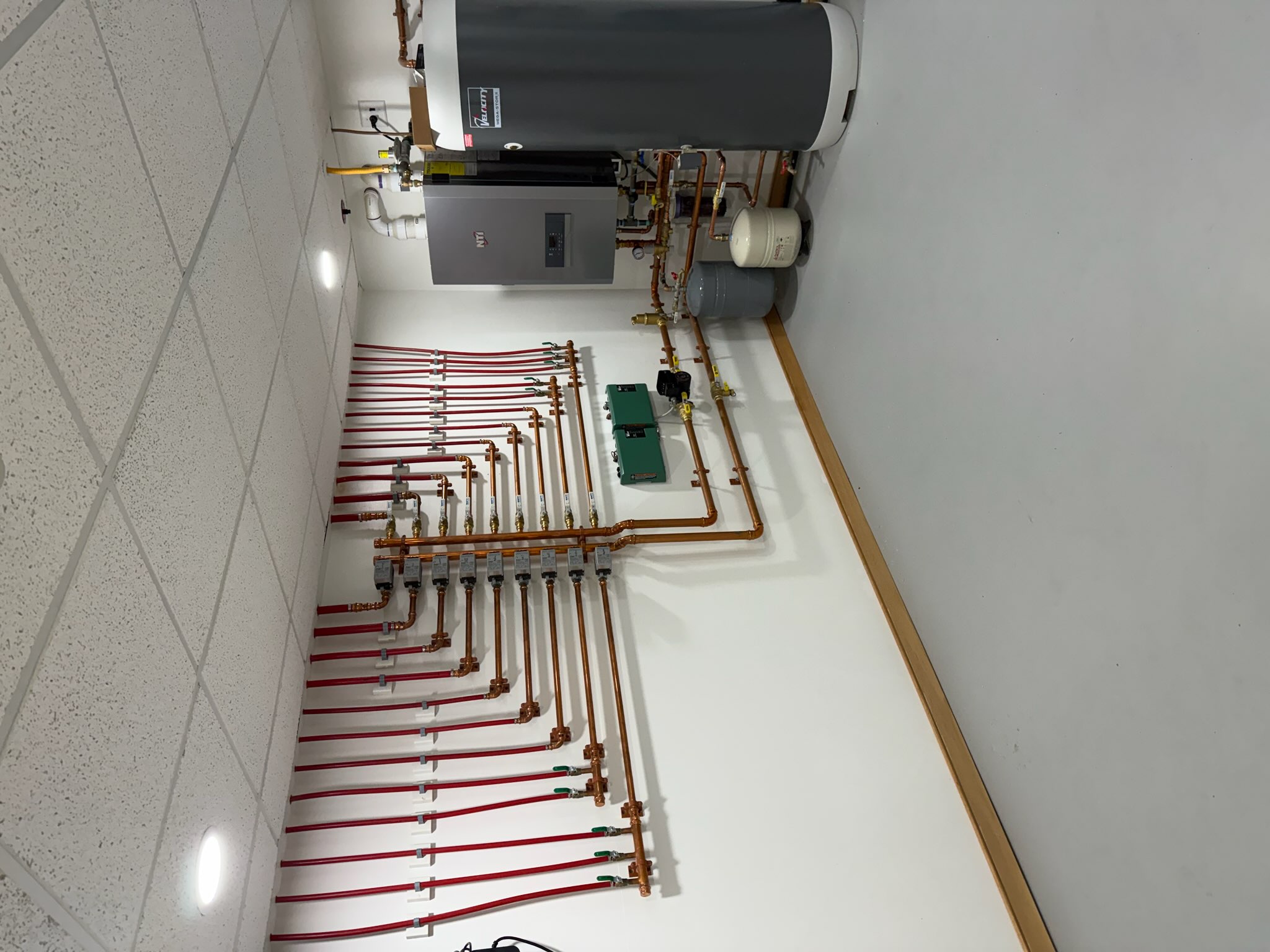 Radiant floor heat installation with color-coded distribution lines and boiler